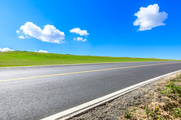 Asphalt highway road and green meadow with mountain nature landscape under blue sky