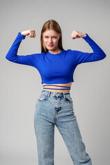 Smiling Young Woman in Blue Top Celebrating Success With Raised Fist - 786901801