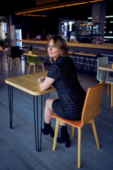 stunning young adult woman in a modern cafe bar sitting at a table