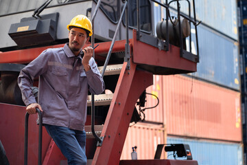 Asia logistic engineer man worker or foreman use walkie talkie direct driver forklift container at...