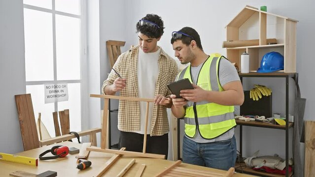 Two men collaborating in a well-lit carpentry workshop, discussing over a wooden frame with tools around them.