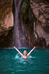 Blonde woman bathing in lake with waterfall behind.jpg