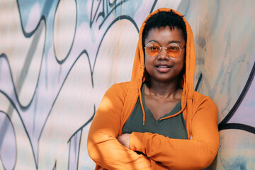 african american woman in sweatshirt posing on graffiti wall