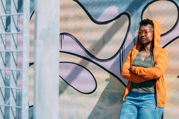 black woman with arms crossed on graffiti wall