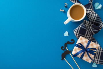 Top view of a Father's Day celebration setting with a stylish plaid tie, coffee mug, gift box with blue ribbon, and decorative elements on a blue background