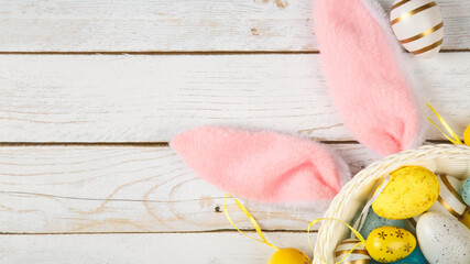 easter holiday background with bunny ears and easter eggs on wooden table. copy space