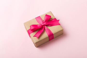 Wrapped christmas or other holiday handmade present in craft paper with colored ribbon. Present box, decoration of gift on table, top view with copy space