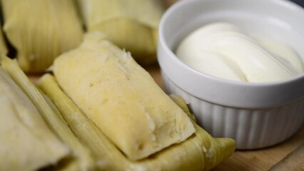A close-up video showcases Central American, latina American tamales wrapped in corn leaves with creamy accompaniment - Powered by Adobe