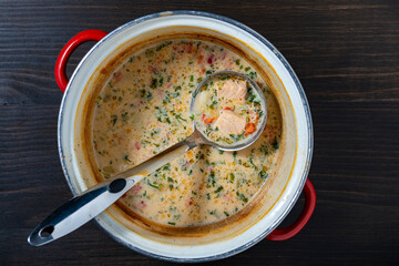 Leftovers cream fish soup in a saucepan with a ladle on a wooden table, closeup, top view - 786946458