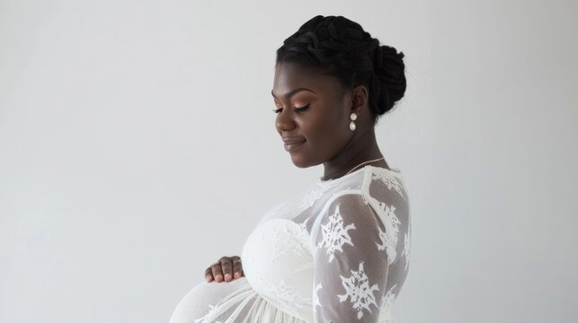 A pregnant woman lovingly holds her baby bump against a white backdrop. The image evokes the emotions and anticipations of pregnancy, motherhood, and the arrival of a new life.
