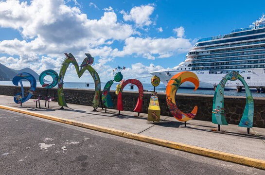 Roseau, Dominica - November 24, 2023: Dominica word sign in front of Oceania Cruises Vista ship in cruise port of Roseau.