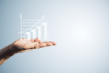 Close up of male hand holding white growing business chart on light background with mock up place....