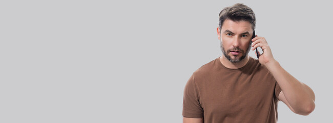 Man using mobile phone isolated over studio background. Man using smart phone cellphone for calls, social media, mobile app. Guy talking on the phone. Banner for header, copy space. Poster for web.