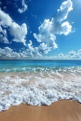 Idyllic tropical beach with waves crashing on sandy shore, clear blue ocean under a sunny sky with clouds.