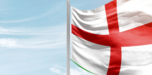 England national flag with mast at light blue sky.