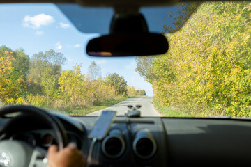 A man in a car checks the road using a navigator from a mobile phone