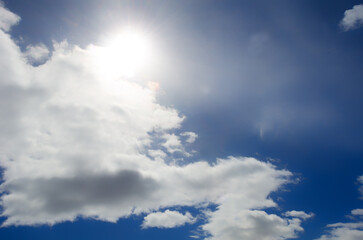 Bright light of the sun on a dark blue sky among the clouds.