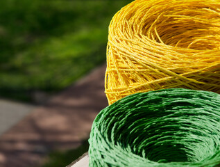 Rolls of yellow and green raffia close-up. Skeins of multi-colored raffia against the background of...