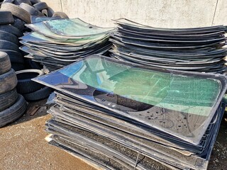 A pile of broken windshields and old car tires