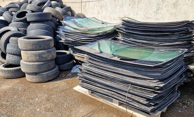 A pile of broken windshields and old car tires
