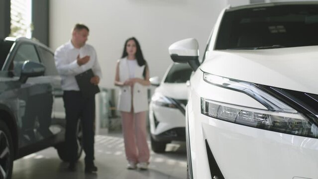 An interested buyer consults with a car dealership manager about the models and characteristics of a modern electric car. Concept of buying and selling a car, deal.