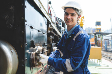 A man in a blue and white uniform is smiling as he works on a train. Concept of pride and...
