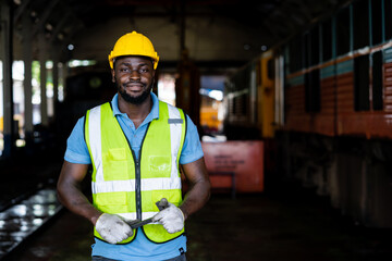 A man in a yellow vest and a hard hat is standing in a train station