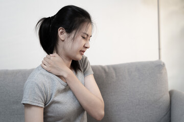 Tired woman touch stiff neck feeling hurt joint back pain rubbing massaging tensed muscles suffer from shoulder ache after long computer work study in incorrect posture sit on sofa at home
