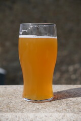 A pint of cloudy craft beer. pint glass on outdoor table 