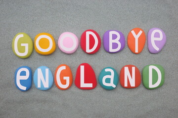 Goodbye England, creative text composed with hand painted multi colored stone letters over green...