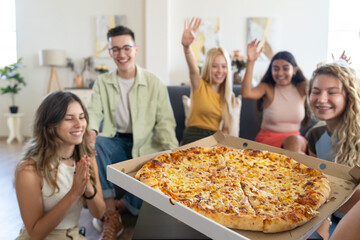 Group of People Sitting Around a Large Pizza