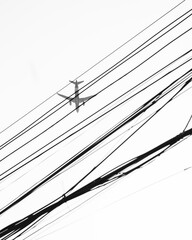 Black and white shot of a plane flying through the sky in a street