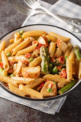 Spicy Chicken Chipotle Pasta with asparagus, bell pepper, green pea and onion closeup in the bowl on the table. Vertical