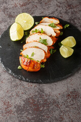 Delicious spicy chipotle chicken breast served with lime and cilantro close-up on a slate plate on the table. Vertical