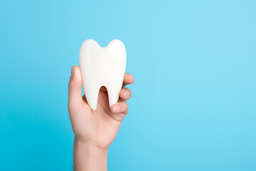 Hand holding toy tooth model. Caries and dental medical care concept