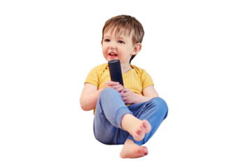 The joyful child is seated on the sofa holding the TV remote, watching cartoons with a beaming smile, isolated on white background.