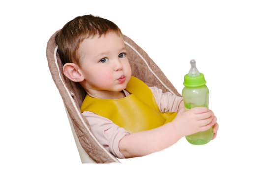 Happy toddler baby drinking from a bottle while sitting on a high chair, isolated on white background. The child boy in the bib has lunch in the home kitchen. Kid aged one year six months - Powered by Adobe