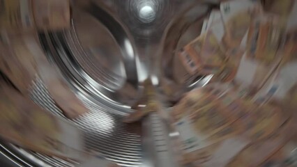Washing a heap of fifty euro bills in washing machine, inside view of drum during spin cycle. Concept of money laundering, financial fraud.