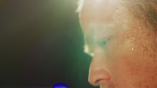 Sweating man looks around while being blinded by light.