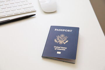 Close up of an American passport on white table, with a pan, a computer keyboard and mouse