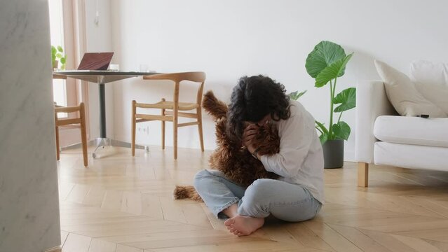 portrait of young woman hugging and kissing her cute curious labradoodle dog. Person spending time at home with his fluffy pet, time to relax stroking pet. Female playing with her dog