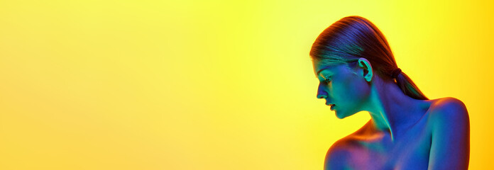 Banner. Portrait of young tender woman with bare shoulders posing in neon light against gradient...