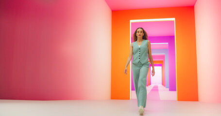Low Angle Portrait of a Fashionable Young Woman Performing a Catwalk in a Colorful Neon Studio....