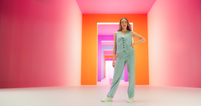 Low Angle Portrait of a Stylish Female Posing Confidently in a Bright Lit Room. Fashionable Young Woman Striking A Pose In Colorful Studio Environment, Working For Luxurious Fashion Brand.