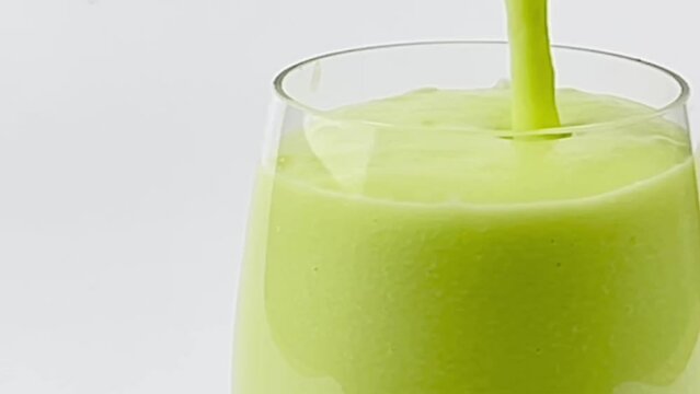 Close up pouring avocado smoothie into a glass isolated white background clipping path