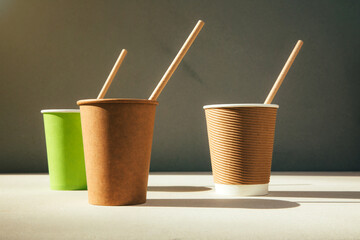 Paper cups with paper straws on a brown cardboard background. Eco friendly, zero waste concept. Front view