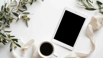 Simple workspace setup with a tablet, a cup of black coffee, white ribbon, and olive leaves on the white table. Mockup