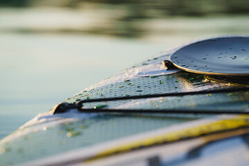 Close up and detail of a Stand Up Paddle board or SUP on the lake with water drops.	