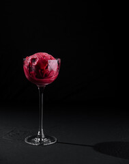 Elegant glass of raspberry sorbet on black background