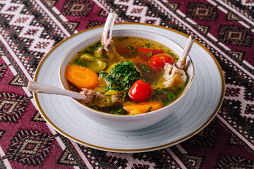 Traditional lamb soup with vegetables on patterned tablecloth